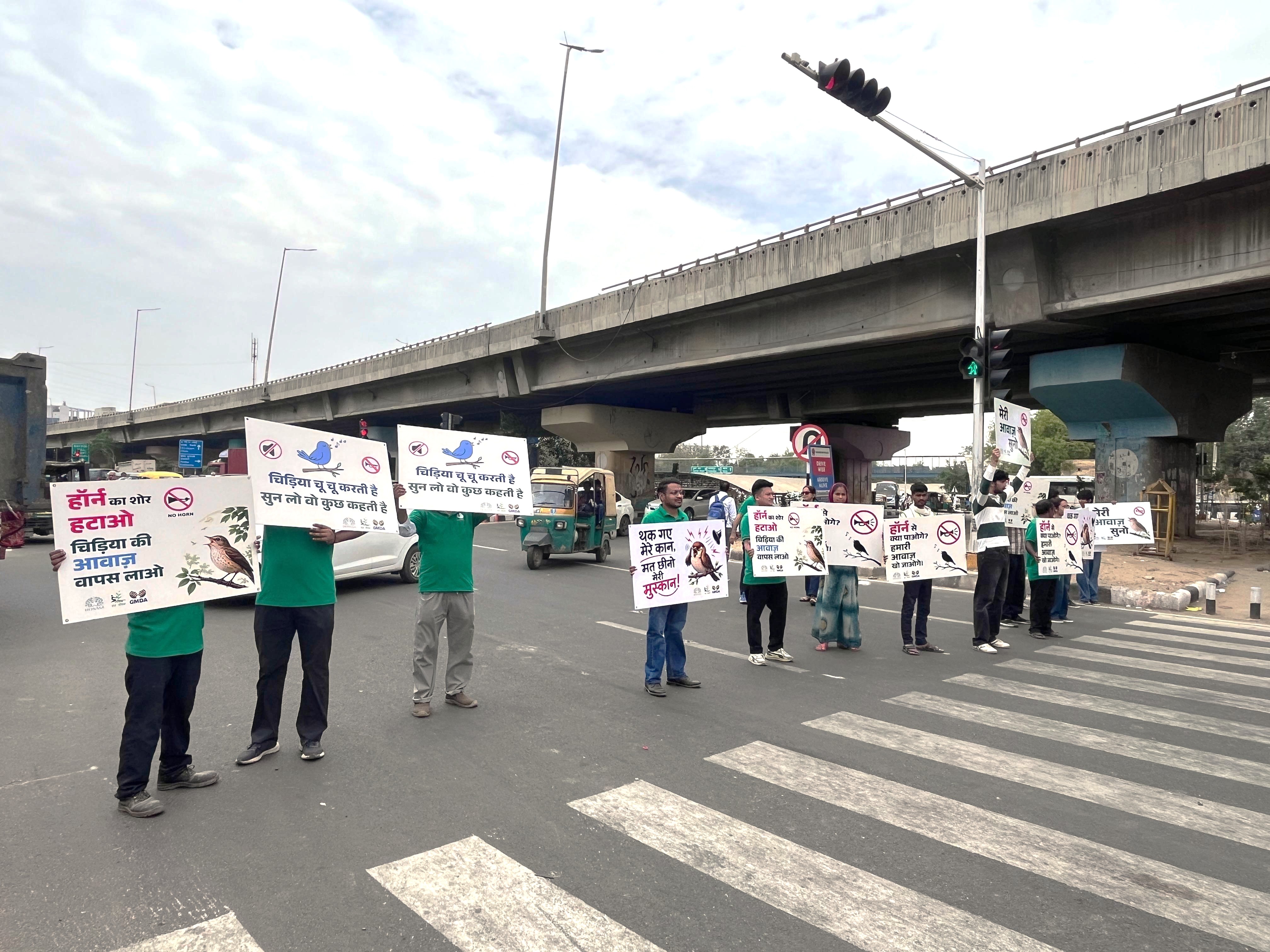 Volunteers holding No Honking placards at traffic junction