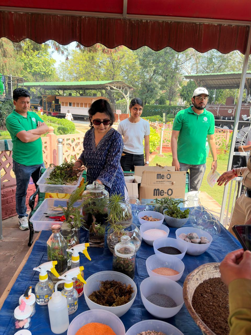 Terrarium setup table with soil layers, plants, and workshop facilitators ready for participants